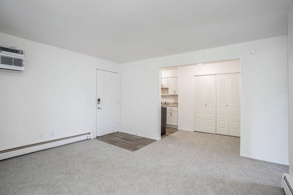 an empty living room with a kitchen in the background at Fairlane Apartments in Springfield, MI