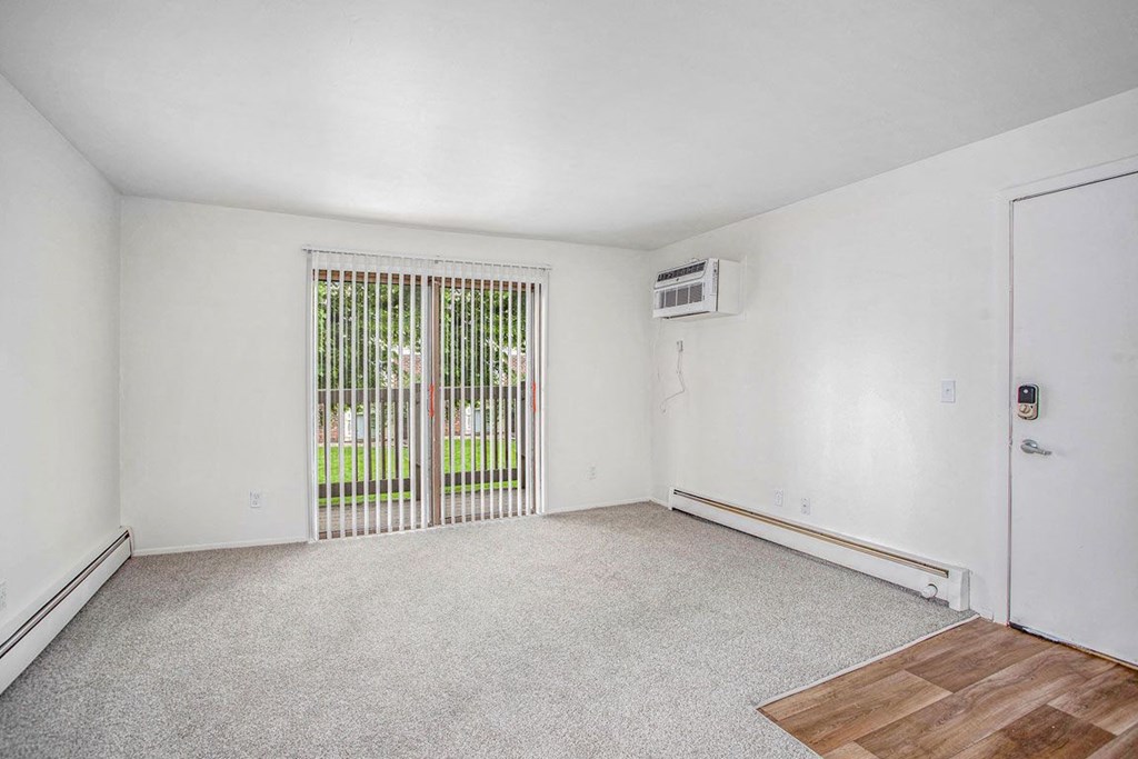 an empty living room with a slider to a private balcony at Fairlane Apartments in Springfield, MI