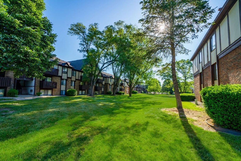 a green courtyard with mature shade trees at Fairlane Apartments, Springfield, MI, 49037