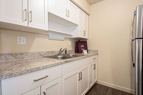 a kitchen with white cabinets and a sink and a refrigerator at Old Farm Apartments, Elkhart, Indiana