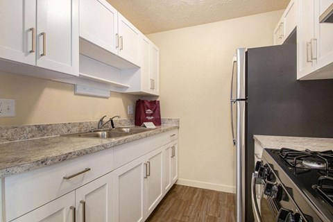 a kitchen with white cabinets and a stainless steel refrigerator at Old Farm Apartments, Elkhart, Indiana