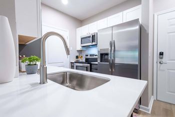 a kitchen with white countertops and stainless steel appliances