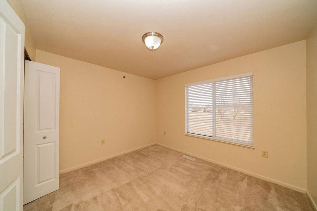 Bedroom with a large window and a closet at Foxwood and The Hermitage, Portage, MI