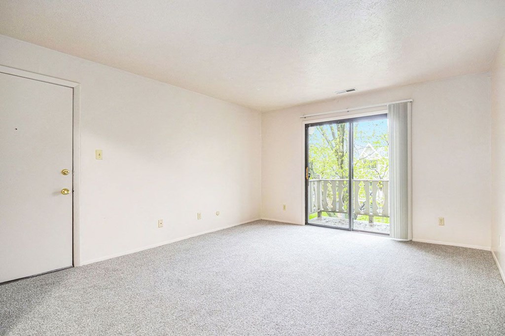 a bedroom with a sliding glass door and white walls at Hickory Village Apartments, Mishawaka, IN
