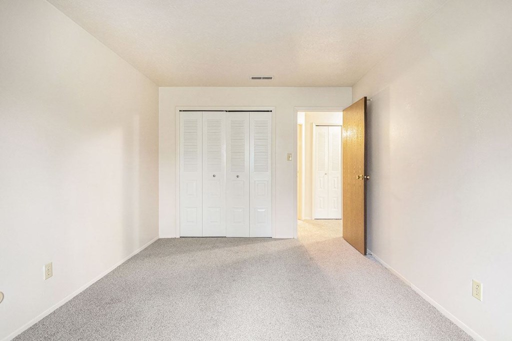 a bedroom with white walls and a white door at Hickory Village Apartments, Indiana, 46545