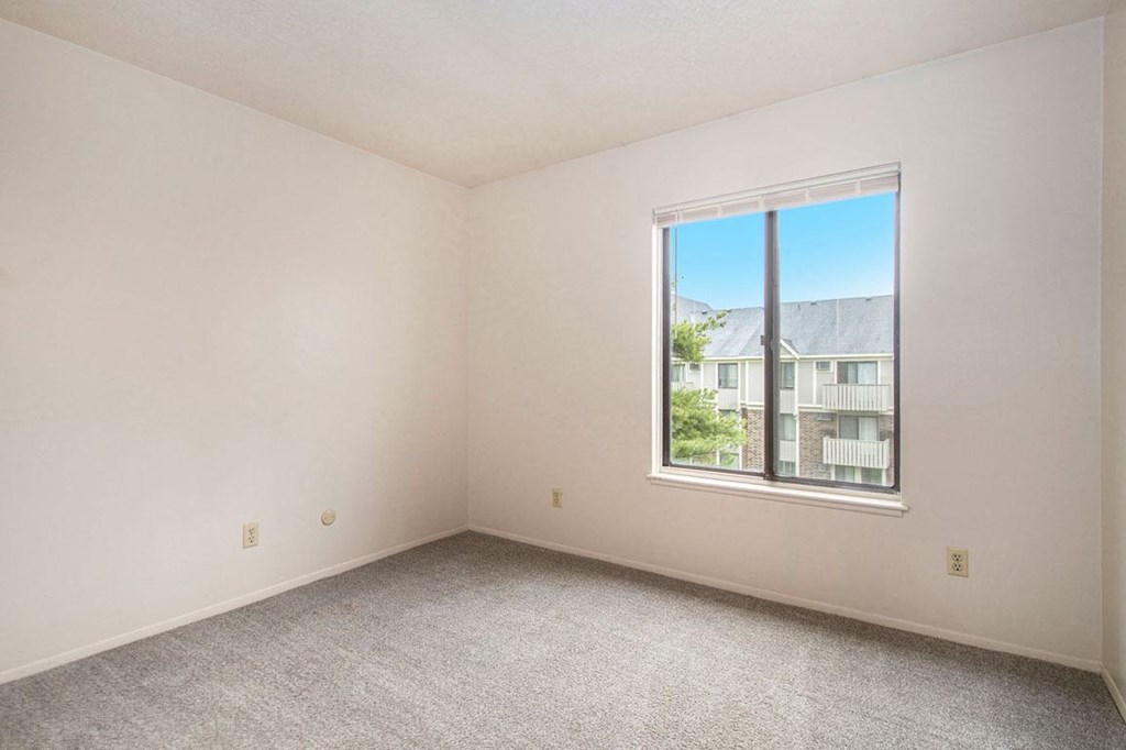a bedroom with a large window and a carpeted floor at Hickory Village Apartments, Mishawaka, IN