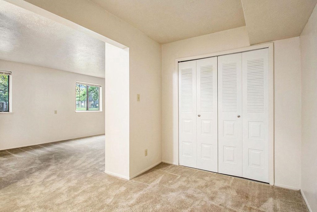 an empty bedroom with a closet and a window at Hickory Village Apartments, Mishawaka