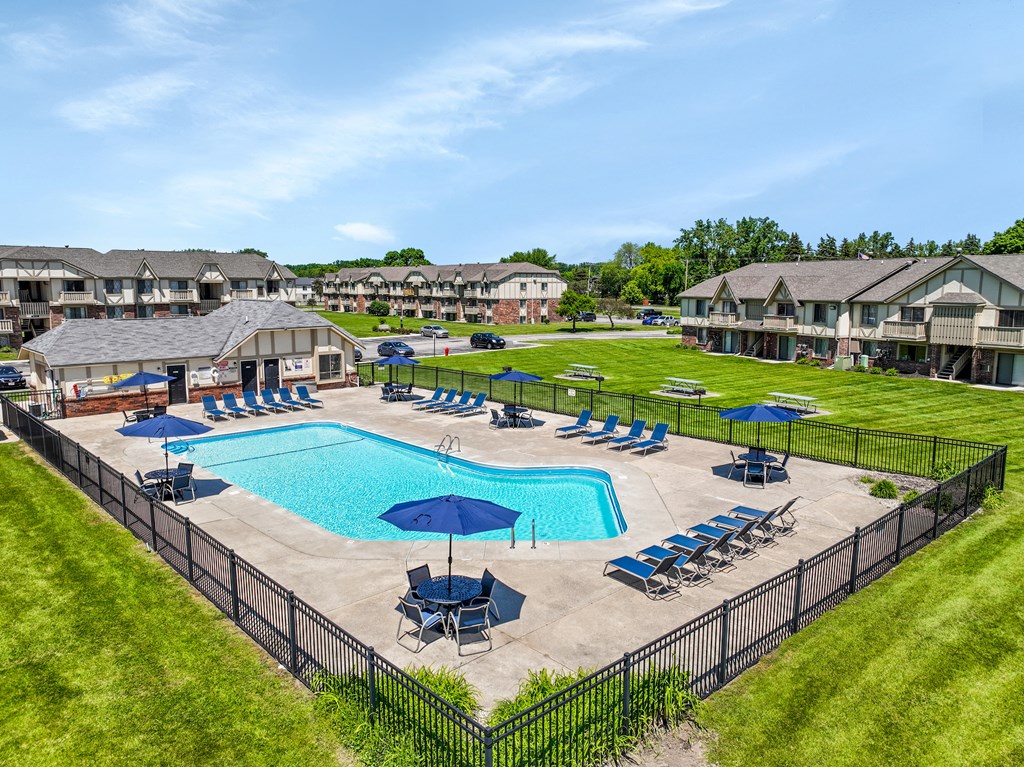 A large swimming pool surrounded by a black fence and lounge chairs.