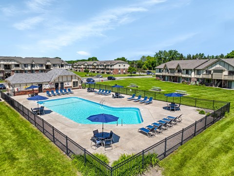A large swimming pool surrounded by a black fence and lounge chairs.