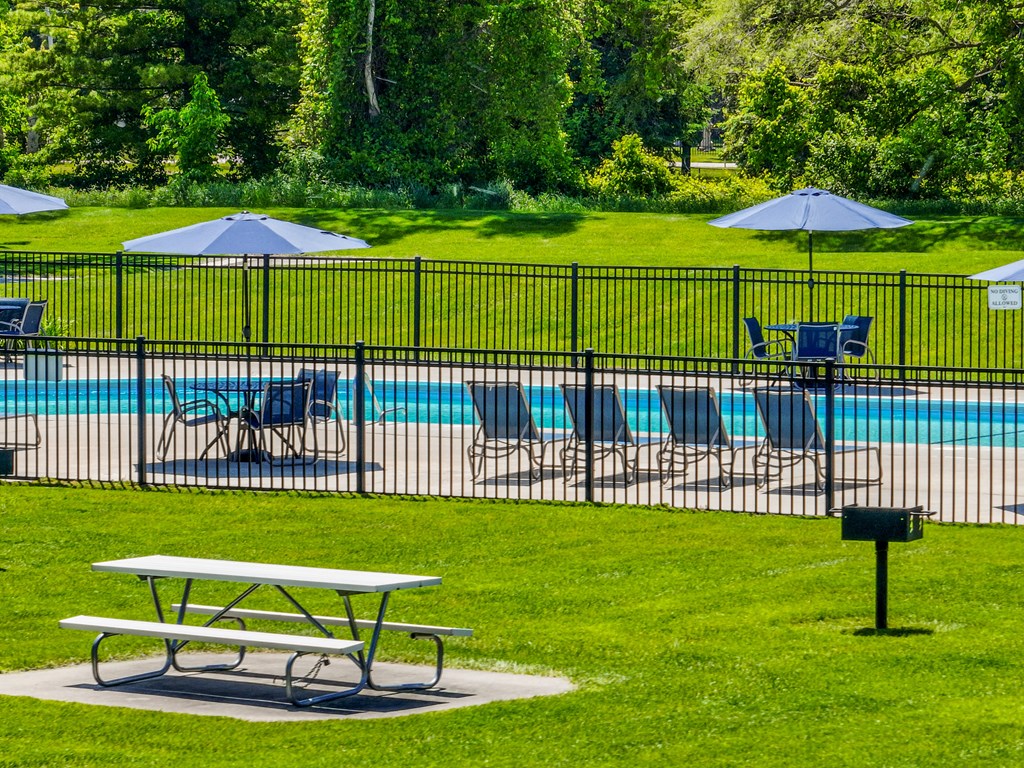 A picnic table is in the foreground of a pool area.