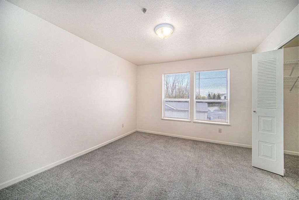 Large bedroom with a walk-in closet and two windows at Hurwich Farms Apartments, Indiana