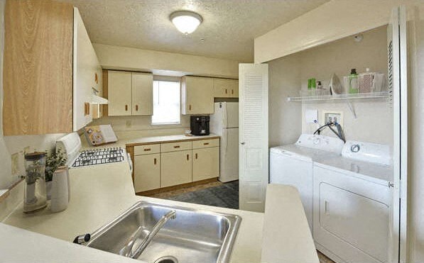a kitchen with a sink and a washing machine at Heatherwood Apartments, Grand Blanc