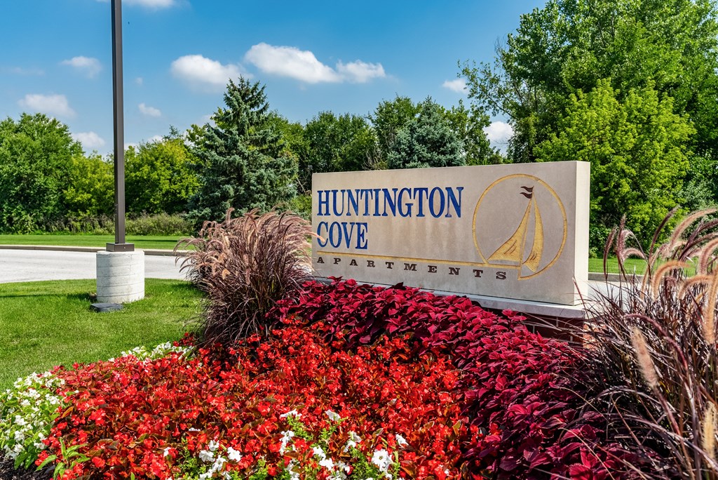 A sign for Huntington Cove Apartments is surrounded by flowers