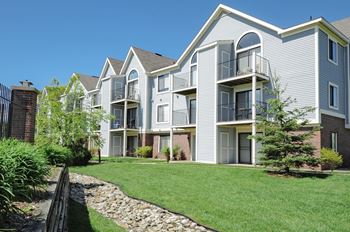 A modern apartment building with a well-maintained lawn in front.