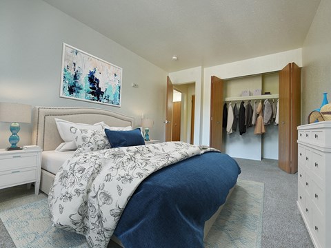 Bedroom with upholstered bed and walk-in closet at Huntington Place Apartments, Essexville