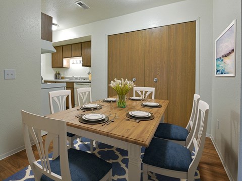 Dining area with wood table and blue cushioned chairs at Huntington Place Apartments, Michigan, 48732