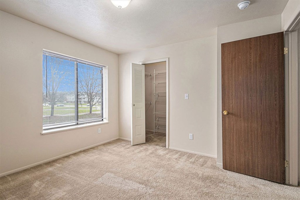 Bedroom with a large window and a door to a closet at Indian Lakes Apartments, Mishawaka