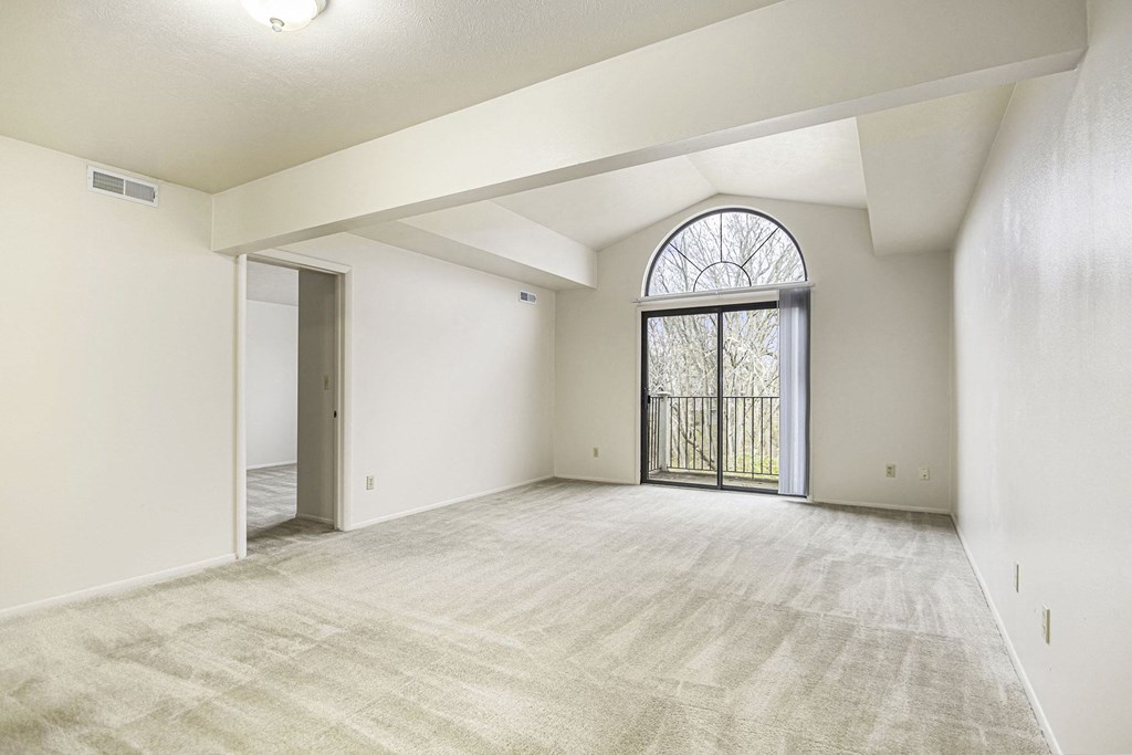 an empty living room with a large window and a door to a balcony at Indian Lakes Apartments, Mishawaka, Indiana