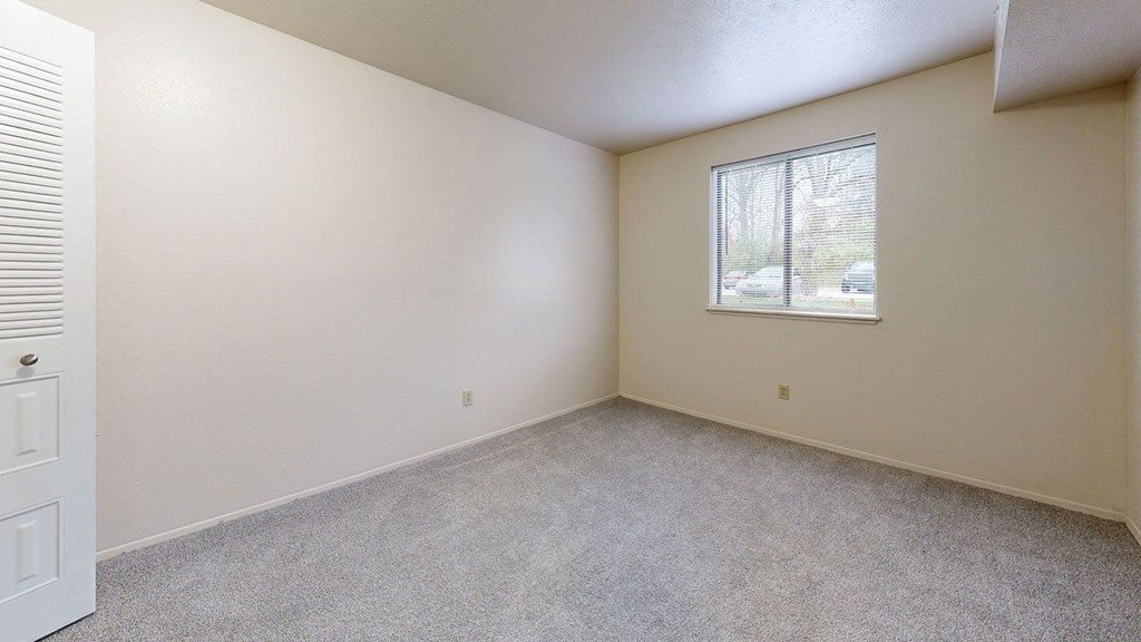spacious bedroom with a window and plush carpeting at Irish Hills Apartments, South Bend, Indiana