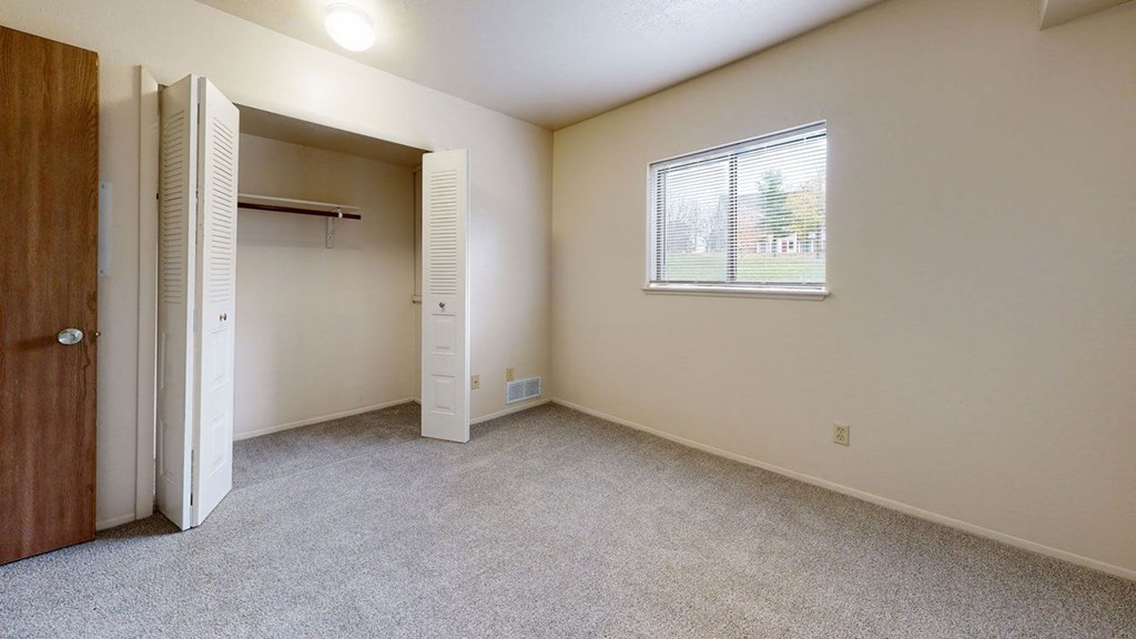 Bedroom with a large closet and a window at Irish Hills Apartments, South Bend