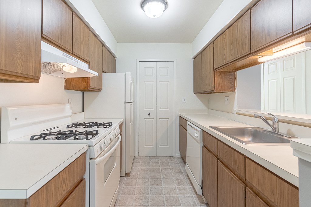 A kitchen with a white stove top oven and a white refrigerator.