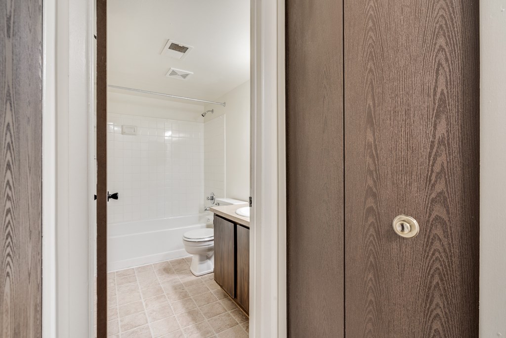 A bathroom with a toilet, sink, and mirror.