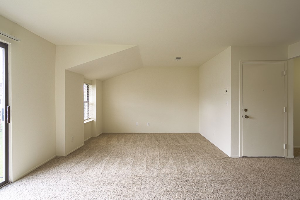 A room with a carpeted floor and a door on the right side.