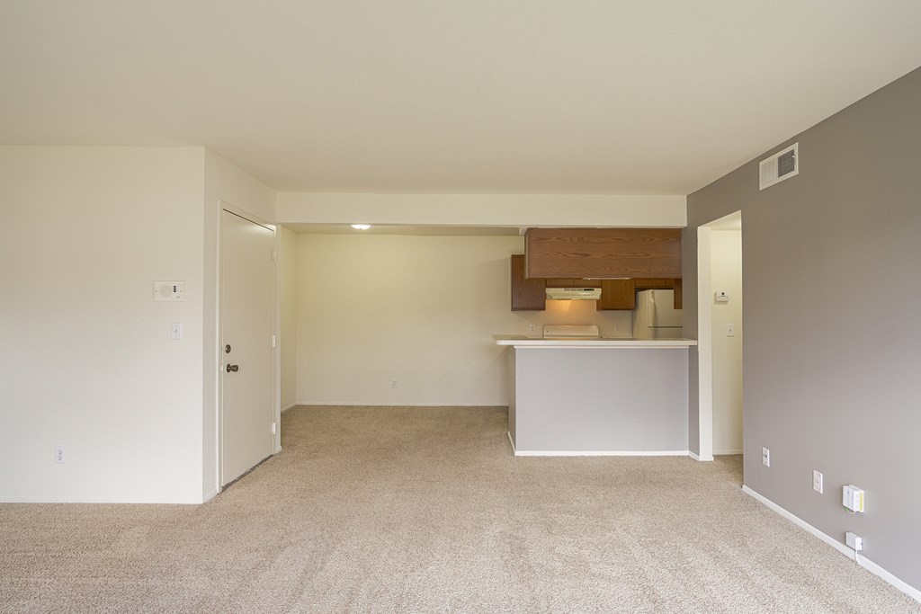 A large, empty room with a carpeted floor and white walls.