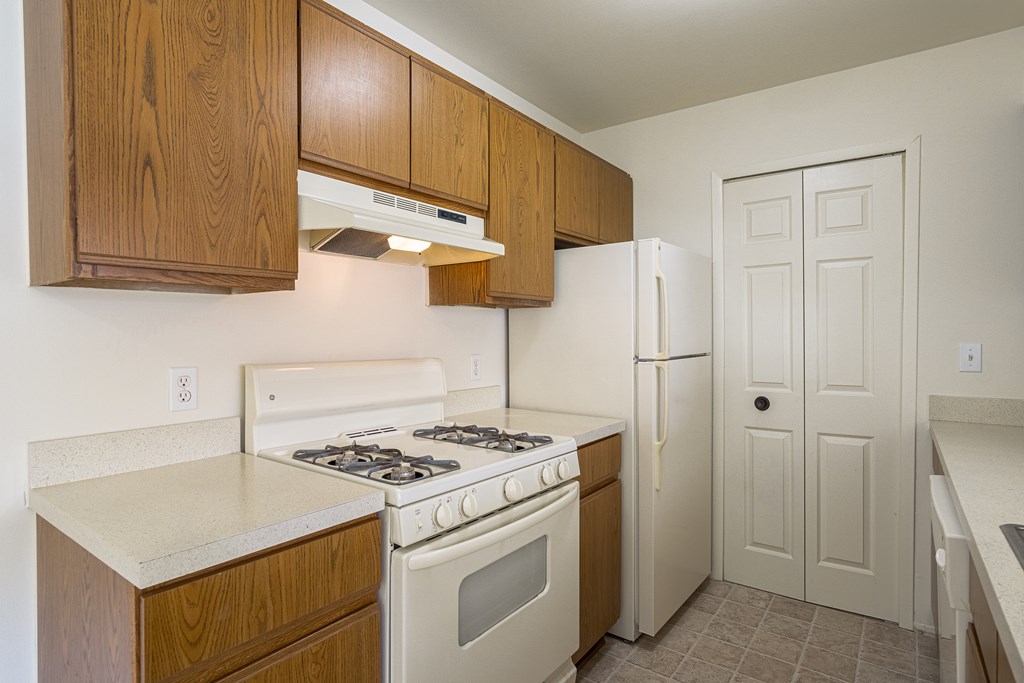 A kitchen with a white stove top oven and a white refrigerator.