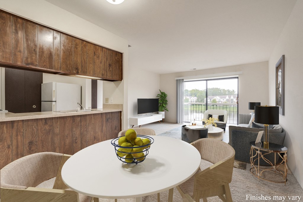 a kitchen and living room with a white table and chairs and a bowl of fruit on the at The Landings Apartments, Westland, MI, 48185