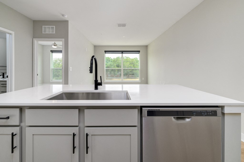 a large white kitchen with a stainless steel dishwasher and sink