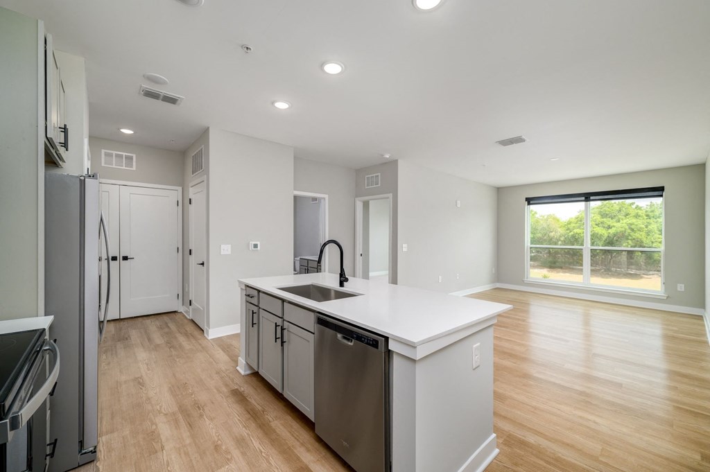 a white kitchen with a large island and stainless steel appliances