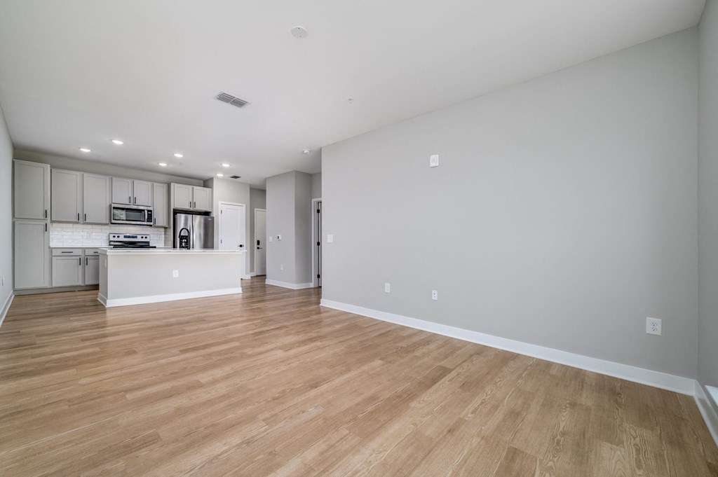 a living room and kitchen with wood floors and white walls