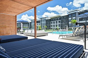 A pool area with sun loungers and a building in the background at Ironwood Flats Apartments, Brandon, FL