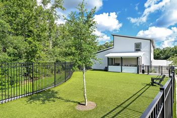 A white house with a black fence and a tree in the front yard at Ironwood Flats Apartments, Florida