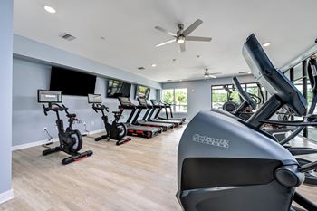 A gym with a variety of exercise equipment including stationary bikes and rowing machines at Ironwood Flats Apartments, Brandon, 33511