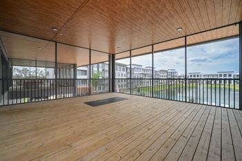 A room with wooden floors and a glass wall overlooking a grassy area.