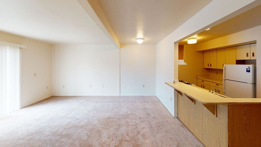 an empty living room and a kitchen and a refrigerator at Liberty Mills Apartments, Fort Wayne