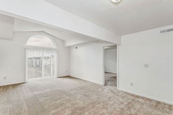 living room with a cathedral ceiling and an arched window to a private balcony