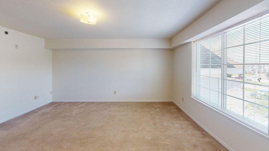 Spacious bedroom with a large window and plush carpet at Limestone Creek Apartment Homes, Alabama