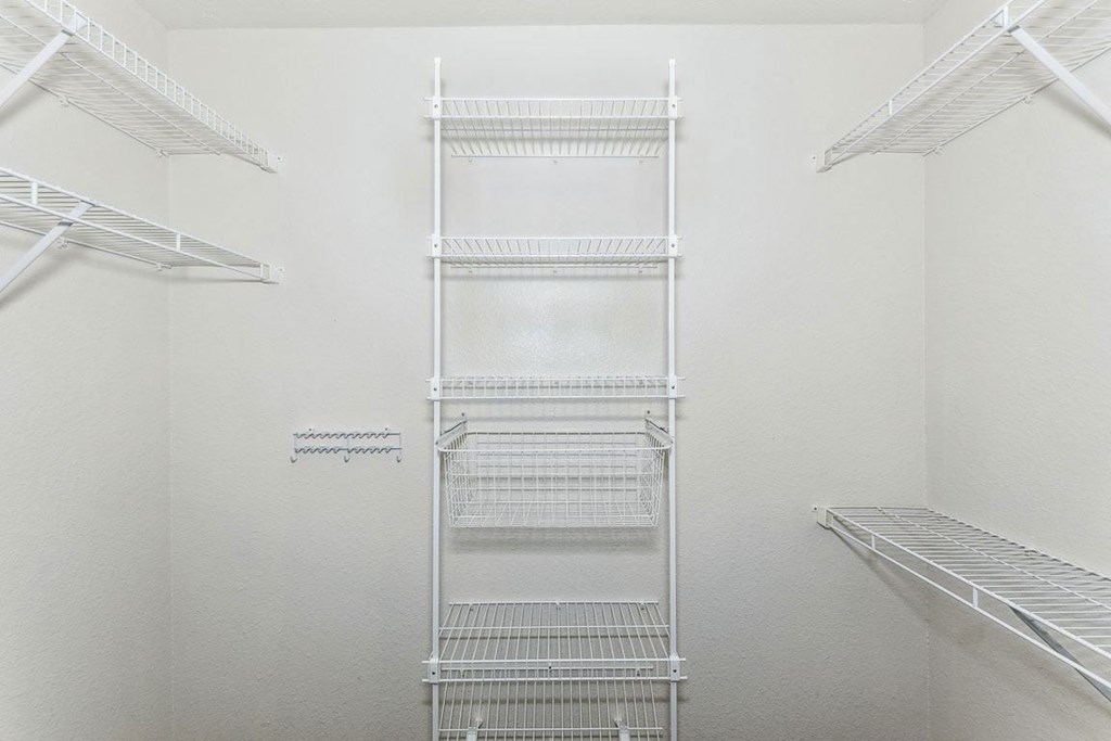a walk in closet with white walls and white metal shelves at Limestone Creek Apartment Homes, Alabama
