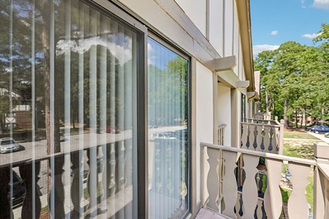 A balcony with a white railing and a glass door.