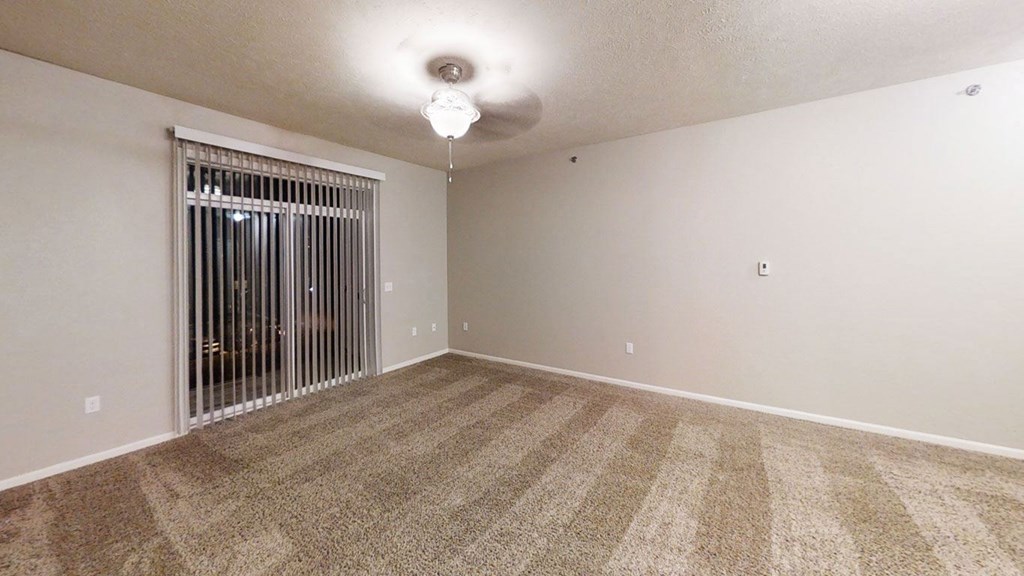an empty living room with a window and a ceiling fan at Lynbrook Apartment Homes and Townhomes, Elkhorn