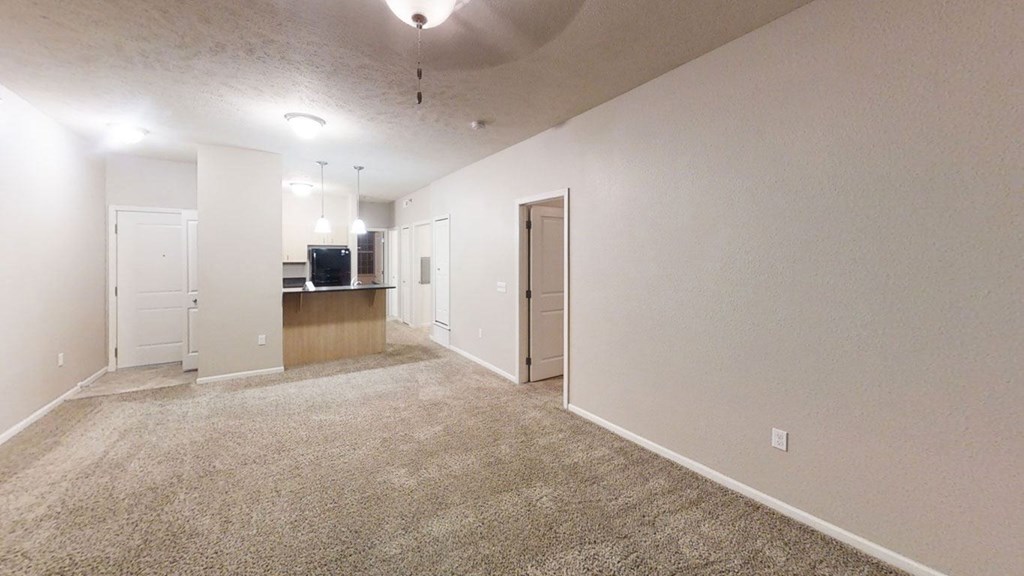 an empty living room and kitchen with a carpeted floor at Lynbrook Apartment Homes and Townhomes, Elkhorn