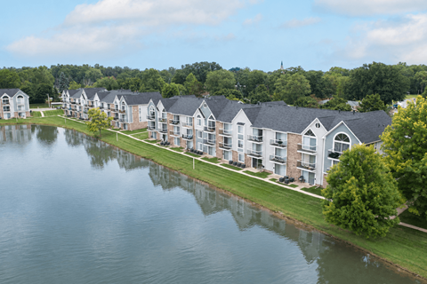 A row of houses are reflected in the water in front of them.