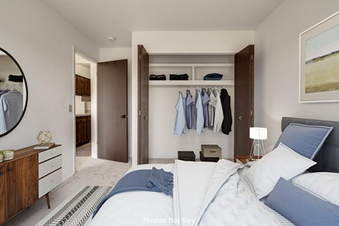 a bedroom with a large bed and a closet with clothes hanging on the wall