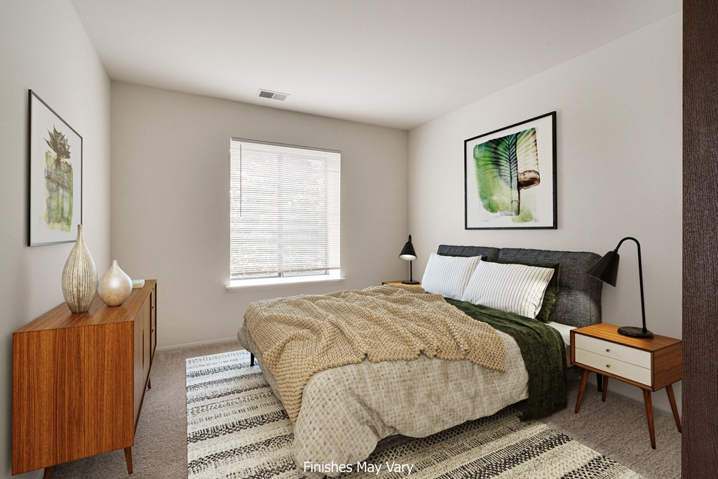 a bedroom with a large bed and a dresser with a lamp on it at The Landings Apartments, Westland, 48185