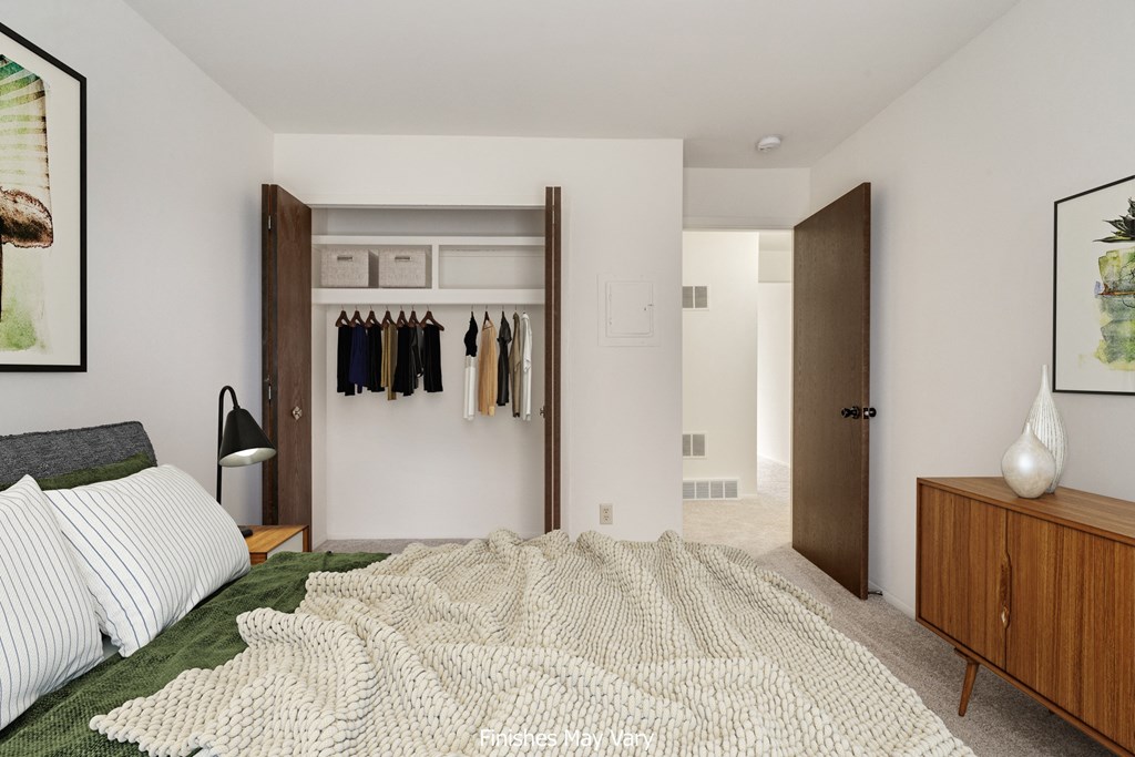 a bedroom with white walls and a large bed with a white blanket a bedroom with white walls and a large bed with a white blanket at The Landings Apartments, Westland, 48185