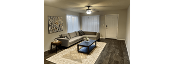 A living room with a grey couch, a coffee table, and a ceiling fan.