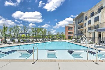 A large outdoor swimming pool with a metal ladder and a metal fence at Luxe 360 on Centerpointe Apartments, Virginia, 23114